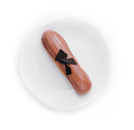 Chocolate eclair on a white plate isolated on white background