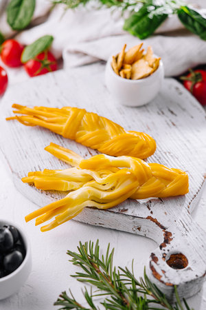 Smoked braided cheese on wooden board