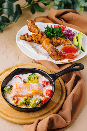 Fried salmon with creamy sauce and pork kebab on a wooden skewerの写真素材