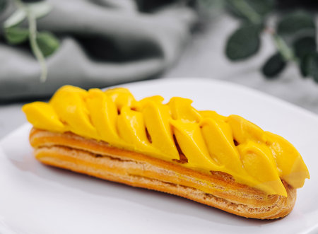 Fresh tasty eclair on white plate closeup