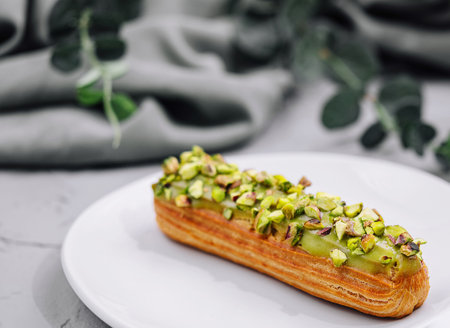 Sweet eclairs with dry pistachios on plate