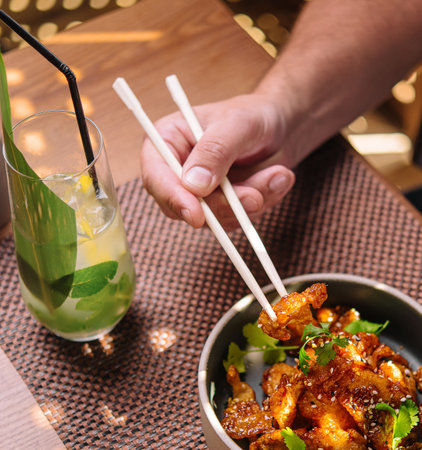 man eating with chopsticks gourmet fried squid Yakuza and drinks sesame and glass of juiceの写真素材