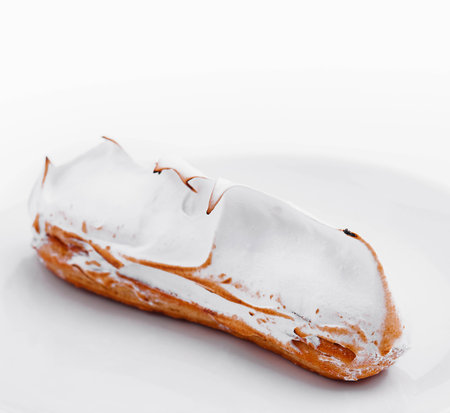 eclair with meringue on white plate