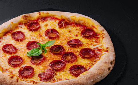 Pepperoni Pizza with Basil and Parmesan Cheese on Black Stone Plateの写真素材
