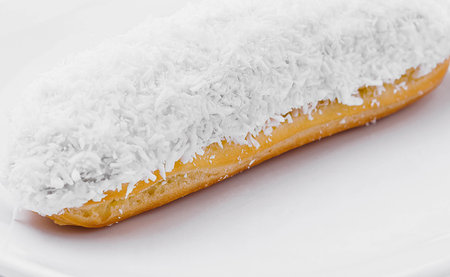 eclair in white glaze and coconut flakes