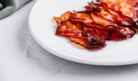 Plate with tasty bacon slices on stoneの写真素材