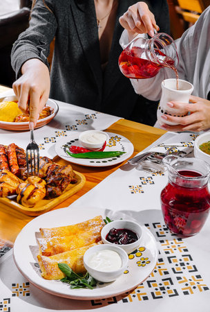 Close-up view of a table with friends sharing a diverse brunch spread, pouring drinks and eating