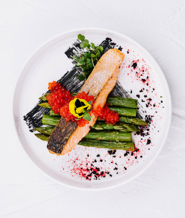 Elegant presentation of salmon with red caviar and green asparagus on a white plateの写真素材