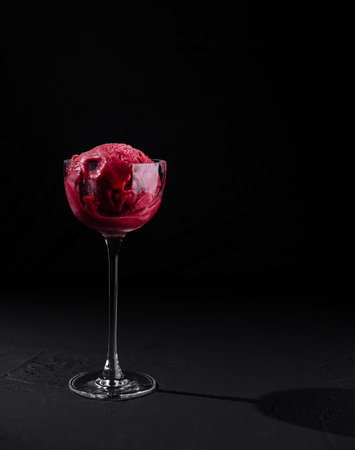 Close-up of a tempting raspberry sorbet served in a delicate glass against a dark backdropの写真素材