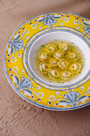 Elegant ceramic plate with traditional italian tortellini sprinkled with herbs on textured backgroundの写真素材