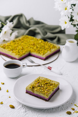 Tempting slice of pistachio cake paired with a fresh cup of coffee, elegant table settingの写真素材
