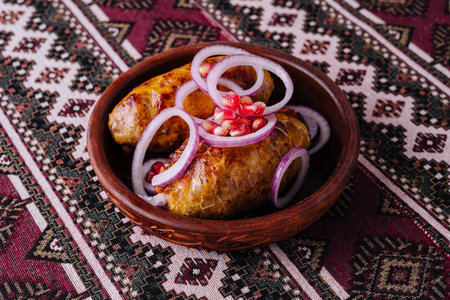 Shkmeruli, a georgian chicken dish in a rustic bowl, garnished with onions and pomegranate seeds