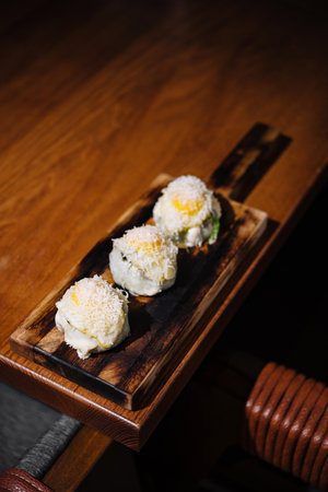 Exquisite sushi rolls topped with white roe, served on a rustic wooden boardの写真素材