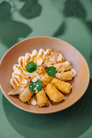 Elegant presentation of crepes with creamy filling and garnish on a modern plate, casting shadowsの写真素材