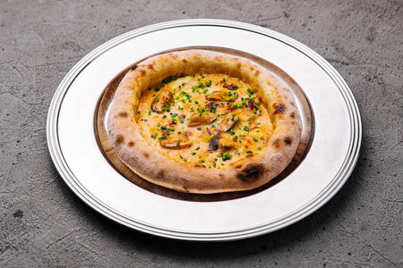 Freshly baked cheese pizza with herbs in a rustic settingの写真素材