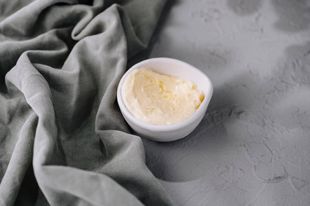 Top view of a bowl of fresh butter placed delicately on a gray linen clothの写真素材