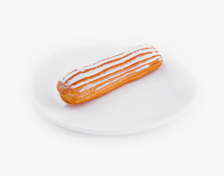 Delicate eclair with icing on a white plate, isolated with clipping path