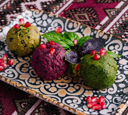 Exquisite vegan appetizer served on a patterned plate, garnished with pomegranate seeds and fresh basilの写真素材