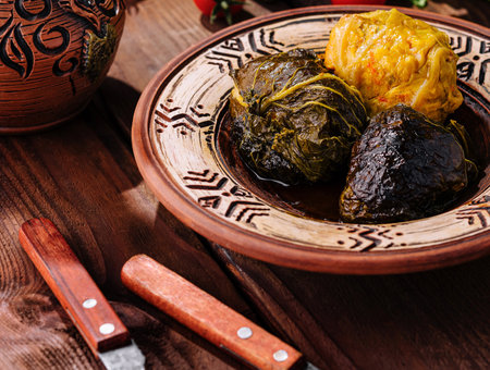 Dolma - seasoned rice wrapped in grape leaves, served on handcrafted plate with fresh vegetables