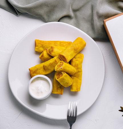 Top view of tasty spring rolls on a plate with sauce