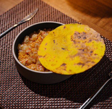Rustic presentation of a classic indian dish featuring a fresh roti and spicy chutney on a wooden tableの写真素材