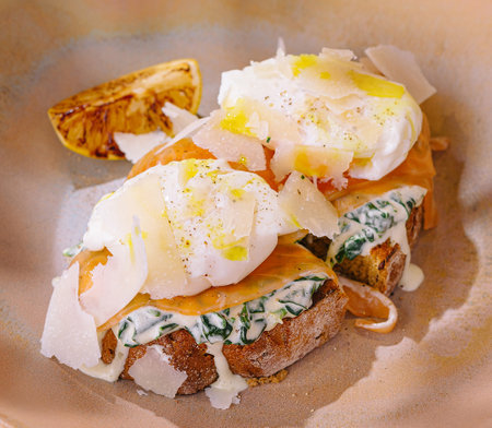 Elegant brunch dish featuring poached eggs on a herb-infused toast, garnished with spicesの写真素材