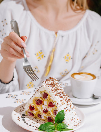 Close-up of a woman about to eat a slice of pavlova, with a coffee cup in the background