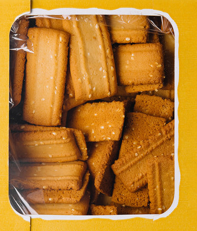Overhead shot of a yellow box filled with golden butter cookies macroの写真素材