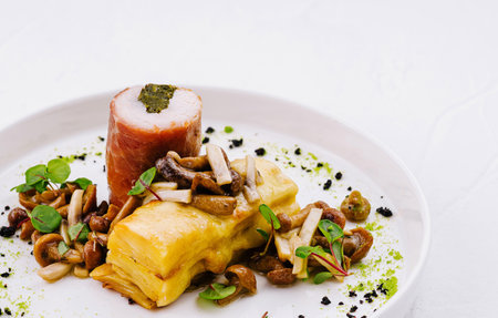 Elegant presentation of stuffed chicken with mushrooms and herbs on a white plateの写真素材