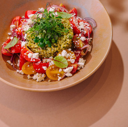 Fresh tomato couscous salad with feta and herbs, beautifully presented in a ceramic bowlの写真素材