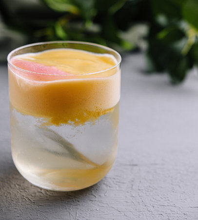 Chilled tropical smoothie with a fresh grapefruit garnish, served in a clear glassの写真素材