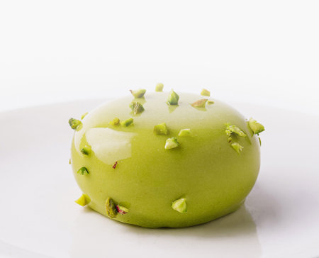 Sophisticated gourmet green apple dessert garnished with edible flowers, presented on a clean white plateの写真素材