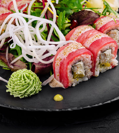 Artistic presentation of sushi rolls with fresh garnishes on a dark backgroundの写真素材