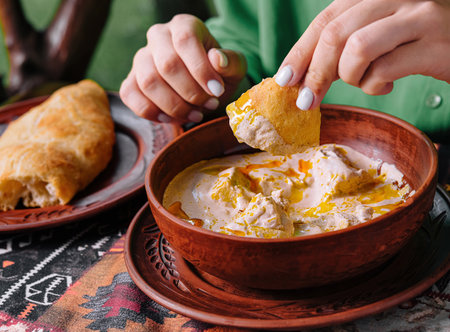Close-up of hands dipping bread in a flavorful bowl of traditional soupの写真素材