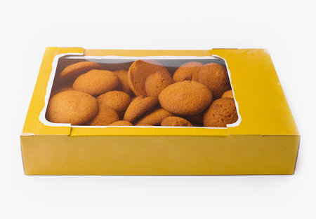 Delicious homemade cookies in a yellow box on a white background, perfect for snack themesの写真素材