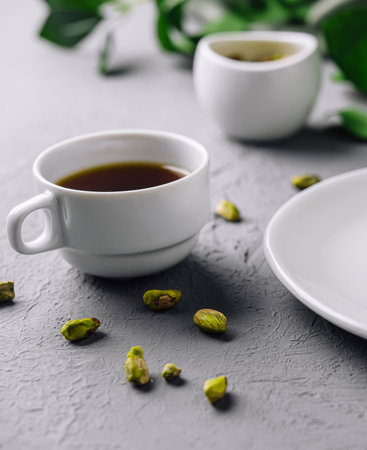 Pistachio nut and white coffee cup on a modern grey backgroundの写真素材