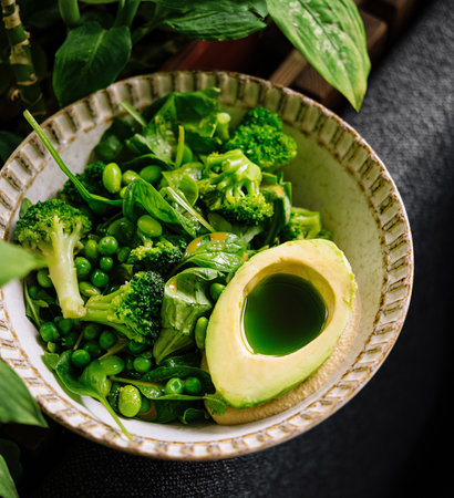 Vibrant green salad with ripe avocado, broccoli, peas and mixed greens in a ceramic bowl