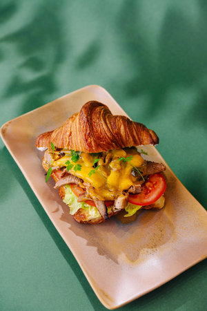 Delicious croissant sandwich with succulent fillings presented on a stylish plateの写真素材