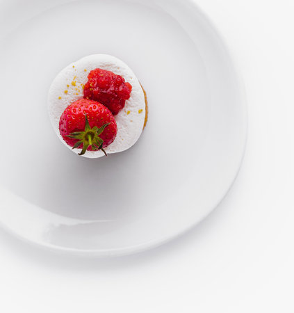 Single ripe strawberry atop a dusted sweet dessert on white plate, top viewの写真素材