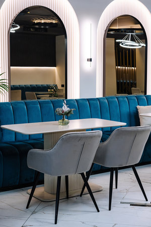 Elegant cafe interior showcasing a chic blue velvet sofa, marble flooring, and sophisticated lightingの写真素材