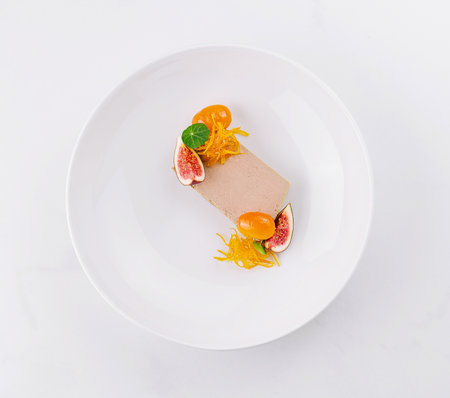 Modern plated dessert with fresh fruits and artistic garnishing, served on a sleek white backgroundの写真素材