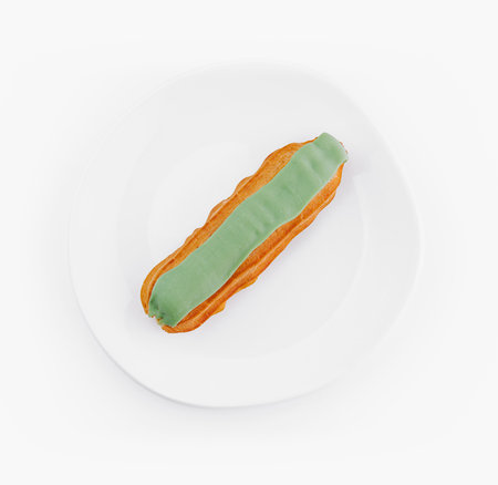 Overhead view of a delicious eclair with green icing on a clean white plate, isolated on a white...