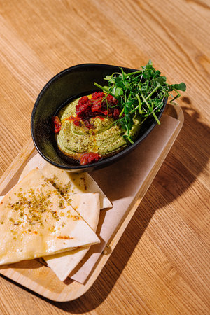 Elevated angle of a bowl of creamy hummus topped with herbs and sun-dried tomatoes, served with pitaの写真素材