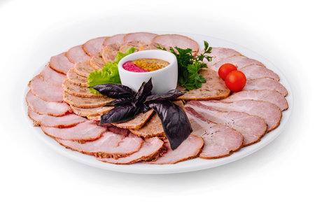 Elegant presentation of sliced roast pork served with mustard sauce, herbs, and tomatoes