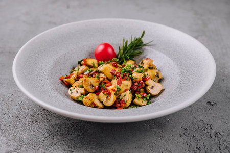 Freshly sauteed mushrooms with herbs garnished with a cherry tomato in a ceramic bowlの写真素材