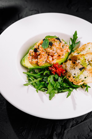 Elegant presentation of avocado and salmon tartare with arugula and toasted breadの写真素材
