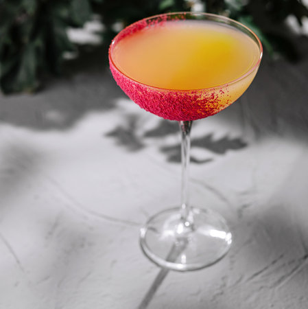 Stylish cocktail glass with a vibrant sugar rim, presented on a sleek, textured backdropの写真素材