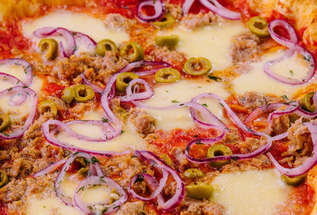 High-resolution image showcasing a vibrant pizza topped with tuna, olives, onions, and melted cheeseの写真素材