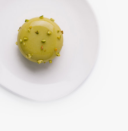 Single pistachio macaron decorated with nuts isolated on a white backgroundの写真素材