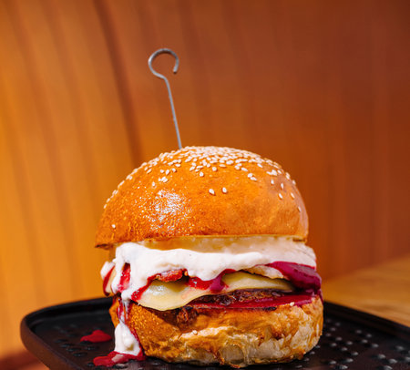 Close-up of a juicy gourmet burger with toppings on a black plateの写真素材